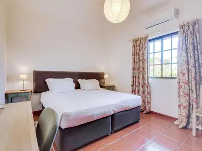 a bedroom with a bed and a large window at Vivenda Pereiras com 2 quartos em Quarteira in Quarteira