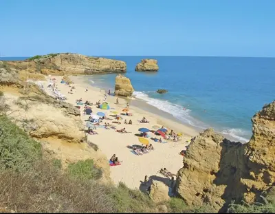 a group of people on a beach near the ocean at Sea view studio, terrace & pools - Albufeira in Albufeira