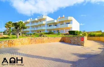 a large white building in front of a stone wall at Sunny Terrace facing the pool and barbecue by Algarve Dream Holidays in Guia