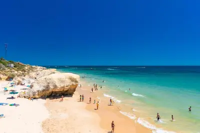 a group of people on a beach with the ocean at Sunny Terrace facing the pool and barbecue by Algarve Dream Holidays in Guia