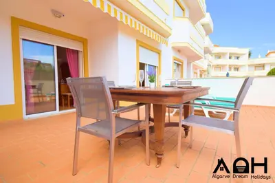 a wooden table and chairs on a patio at Sunny Terrace facing the pool and barbecue by Algarve Dream Holidays in Guia