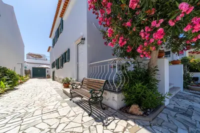 a bench sitting next to a tree with pink flowers at Vivenda Lemos B in Albufeira