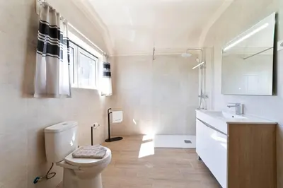 a white bathroom with a toilet and a sink at Vivenda Lemos B in Albufeira