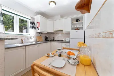 a kitchen with white cabinets and a wooden table at Vivenda Lemos C in Albufeira