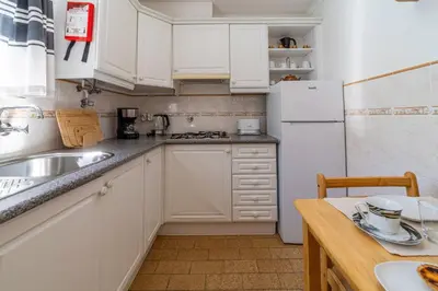 a kitchen with white cabinets and a white refrigerator at Vivenda Lemos C in Albufeira
