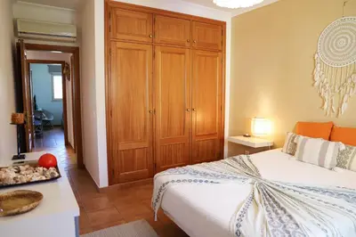 a bedroom with a bed and a wooden cabinet at Atlântida Golf Village by Garvetur in Quarteira