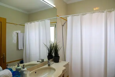 a bathroom with a sink and a white shower curtain at Atlântida Golf Village by Garvetur in Quarteira