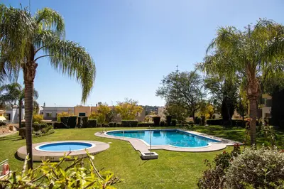 a swimming pool in a yard with palm trees at Terraços do Milénio II by Garvetur in Quarteira