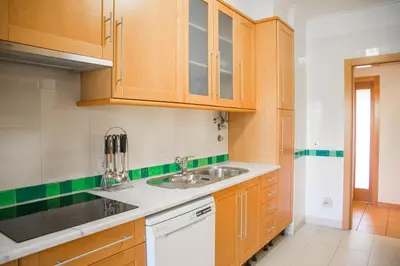 a kitchen with wooden cabinets and a sink at Terraços do Milénio II by Garvetur in Quarteira