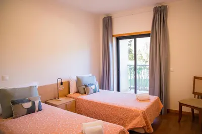 a hotel room with two beds and a window at Terraços do Milénio II by Garvetur in Quarteira