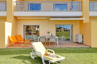a house with a patio with a table and chairs at Jardins da Marina by Albufeira Rental in Albufeira