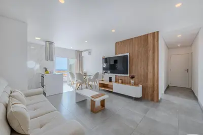 a living room with a white couch and a tv at Alexandra Paradise in Albufeira