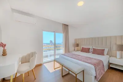 a white bedroom with a large bed and a window at Alexandra Paradise in Albufeira