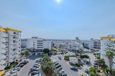 a city street with cars parked in a parking lot at Alexandra Paradise in Albufeira