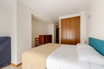 a bedroom with a white bed and a wooden door at Albufeira Coast Apartment by Double Ninety Stays in Albufeira