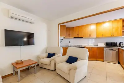 a living room with two chairs and a kitchen at Albufeira Coast Apartment by Double Ninety Stays in Albufeira