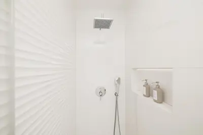 a white bathroom with a shower and a white wall at Top-Floor 2BR, Sea and city Views & Jacuzzi in Faro