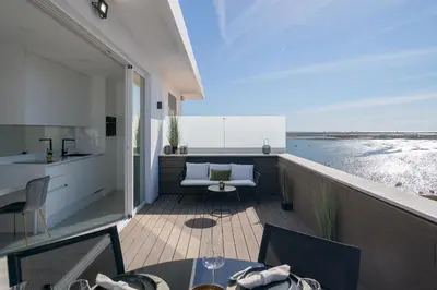 a balcony with a table and a kitchen and the ocean at Downtown, 1br with a first row view over the sea in Faro