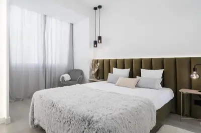 a bedroom with a large white bed and a chair at Downtown, 1br with a first row view over the sea in Faro