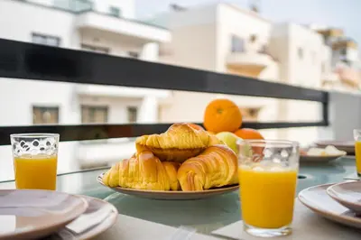 a plate of croissants and oranges on a table with orange juice at Sol & Mar Quarteira in Quarteira