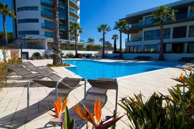 a swimming pool with chairs next to a building at Cavalo Preto Beach Resort Apt & Wi-Fi Nr Beach in Quarteira