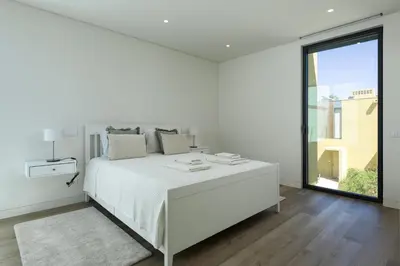 a white bedroom with a white bed and a large window at Vilamoura Parque - Luxury Villa with pool by HD in Vilamoura