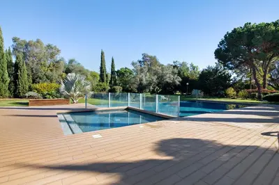 a swimming pool with glass walls in a garden at Casa do Sol and Golf - Vilamoura in Vilamoura