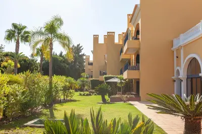 a courtyard of a building with palm trees and plants at Vila Sol F5 Vilamoura 2BR by Enjoy your stay in Quarteira