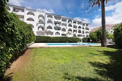 a park with palm trees and a building in the background at Apartamento Machadinho in Albufeira