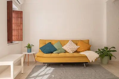 a living room with a yellow couch with colorful pillows at Studio 39 Downtown in Faro
