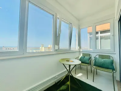 a room with two chairs and a table and windows at Doble Vista Faro, Terrace with View, AC & WiFi in Faro