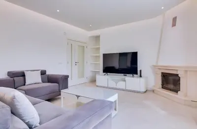 a living room with a couch and a tv and a fireplace at Casa Nuria com 4 quartos, piscina e churrasco em Vale do Lobo in Almancil
