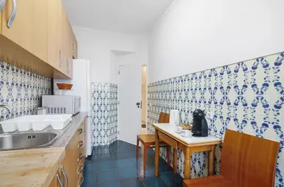 a kitchen with a sink and a table with chairs at Happy House Central Apartment in Faro