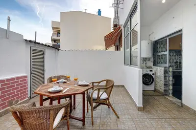 a patio with a wooden table and chairs at Happy House Central Apartment in Faro