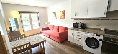 a living room with a red couch and a kitchen at Ocean life in Albufeira