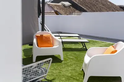 a balcony with white chairs and an orange pillow at Marggisa - City Center by HD in Faro