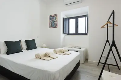 a white bedroom with a large bed with towels on it at Marggisa - City Center by HD in Faro