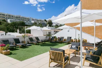 a patio with chairs and tables and white umbrellas at Albufeira Solmare Suites in Albufeira