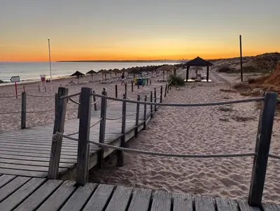 a wooden boardwalk leading to a beach at sunset at Apartamento Vista Piscina in Guia
