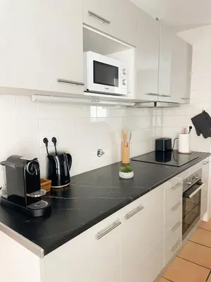 a kitchen with a black counter top with a microwave at Luxury Apartment in Vila Sol Resort in Quarteira