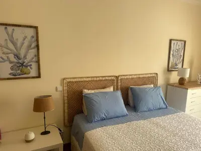 a bedroom with a bed with two blue pillows at Jardins da Marina BQ in Albufeira
