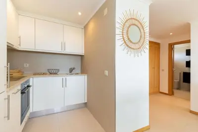 a kitchen with white cabinets and a mirror on the wall at Snazzy Varandas do Castelo By Garvetur One Bedroom Apartment sleeps 2 persons in Albufeira