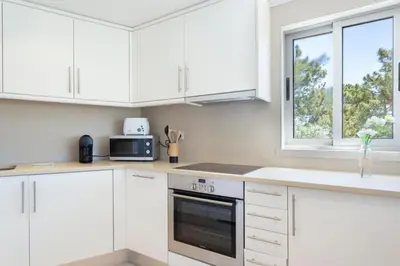 a white kitchen with white cabinets and a window at Snazzy Varandas do Castelo By Garvetur One Bedroom Apartment sleeps 2 persons in Albufeira