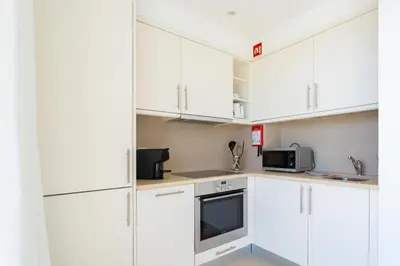 a white kitchen with white cabinets and a microwave at Snazzy Varandas do Castelo One Bedroom Apartment with Sea View sleeps 2persons in Albufeira