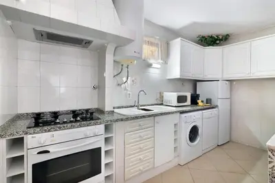 a white kitchen with a sink and a dishwasher at Casa da Várzea in Albufeira