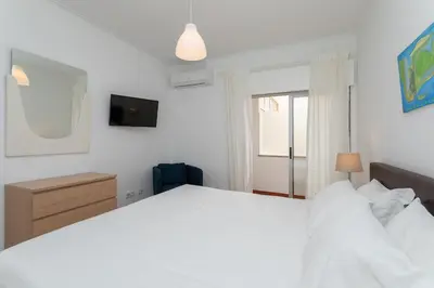 a bedroom with a large white bed and a window at AL - Apartamentos Vista Mar in Quarteira