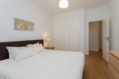 a white bedroom with a white bed and a door at AL - Apartamentos Vista Mar in Quarteira