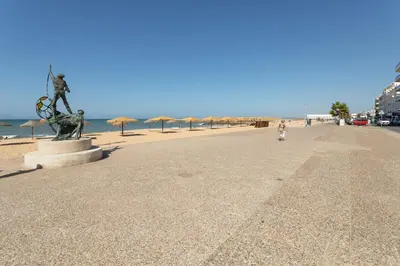 a statue on a beach next to the ocean at AL - Apartamentos Vista Mar in Quarteira