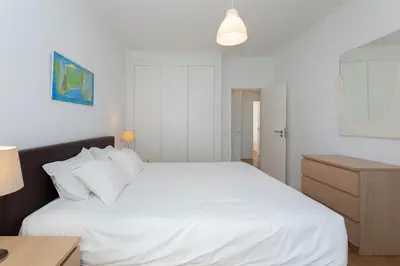 a bedroom with a large white bed with a night stand at AL - Apartamentos Vista Mar in Quarteira
