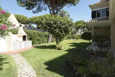 a yard with a white fence and a tree at Vila Popa - Golf Front with Games Room by HD in Vilamoura